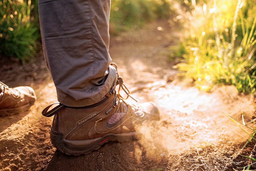 Close up of a hiking boot on a dusty trail.