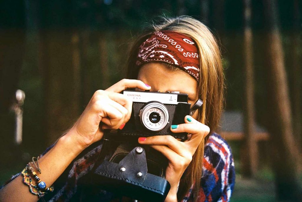 Woman holding vintage camera up to her eye.